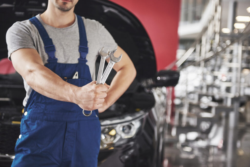 Hands of car mechanic with wrench in garage.